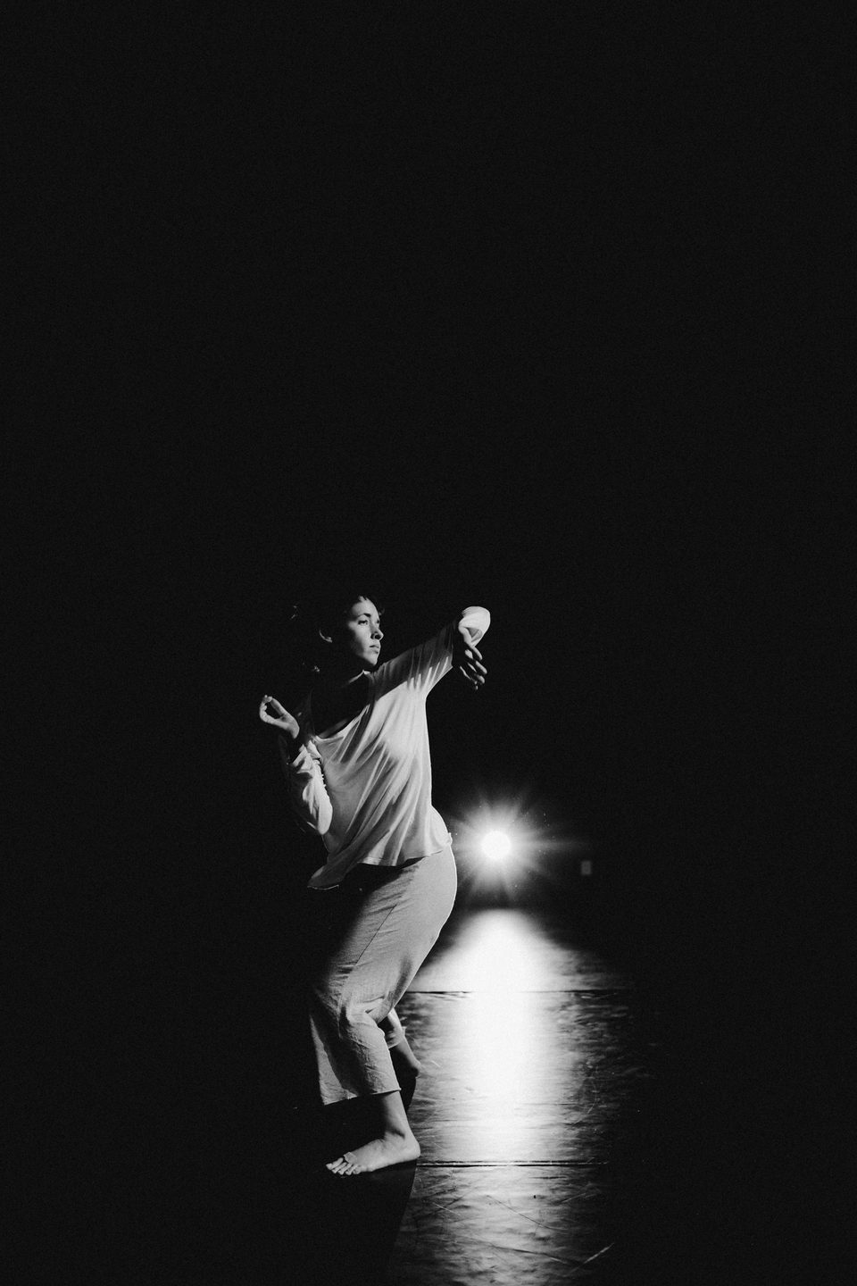 dancer arms up bright light behind